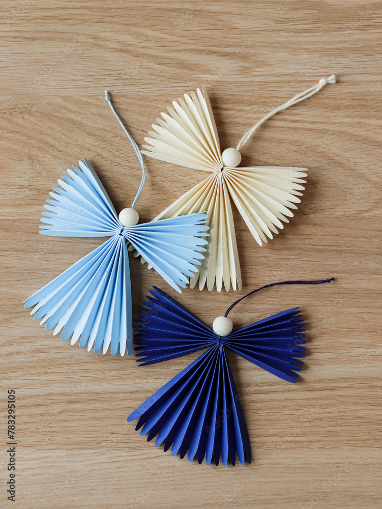 Three flying origami angels with cotton ropes on wooden background Three flying origami angels with cotton ropes on wooden background