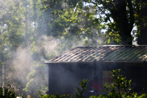 Pożar małego budynku, widoczny dym i płomienie