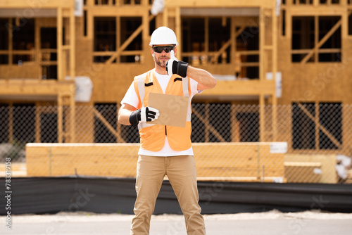 Man Contractor holds piece of empty cardboard sign in his hands. a male construction worker in a helmet stands in a construction zone with empty cardboard. Construction Worker on Duty