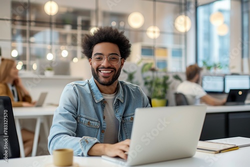Happy successful modern young mixed race businessman working with his laptop at his office 