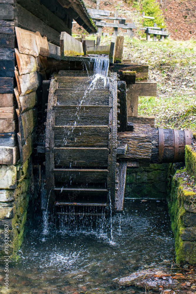 the flow of water falling from the trough to the water wheel. Water, water wheel, ancient technology, natural element, natural energy the flow of water falling from the trough to the water wheel. Water, water wheel, ancient technology, natural element, natural energy