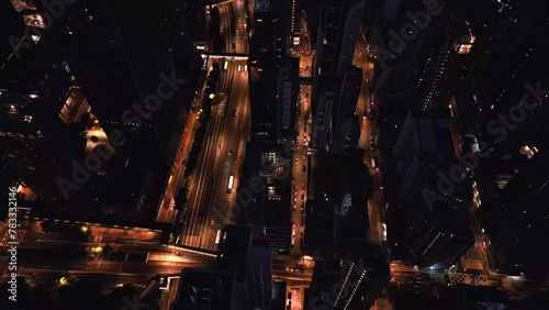 Drone scenery of Hong Kong in the evening filmed by drone in time lapse. There are high skyscrapers with flashing lights and cars driving along narrow streets. Travel to Asia to admire architecture photo