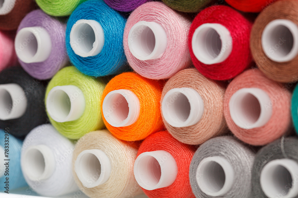 multi-colored spools of sewing thread on a white background