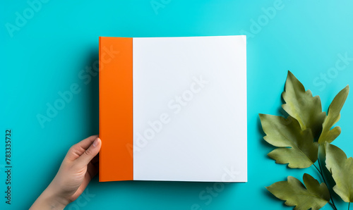 Woman's hand holding blank brochure or book mockup on blue background, showcasing offset paper leaflet or booklet template in A5 size photo