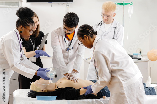 Group of people learning how to make first aid heart compressions with dummies during the training photo
