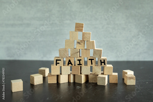 Stack of small building blocks with the word faith hand written on them piled in a pyramid