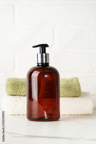 Soap bottle and towel stack on white bathroom background.