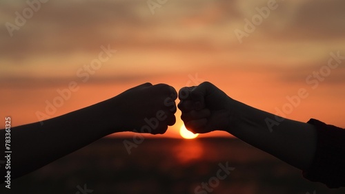 Hands clashing fists brofist at sunset in field. Farmers workers colleagues employees partners working in agricultural field lawn glade on farm hit fists shake hands interact. Teamwork friendship.