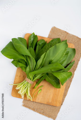 A bunch of wild garlic on a kitchen board on a light background, top view.