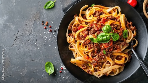 Pasta fettuccine with beef ragout sauce in black bowl. Grey background. Copy space. Top view.