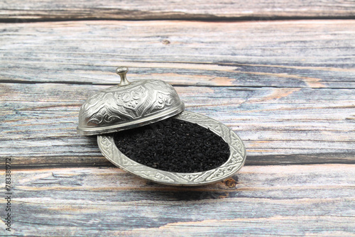 Black cumin seeds and essential oil with bowl and wooden shovel or spoon. Nigella Sativa in glass bottle. Organic herbal medicine for many diseases