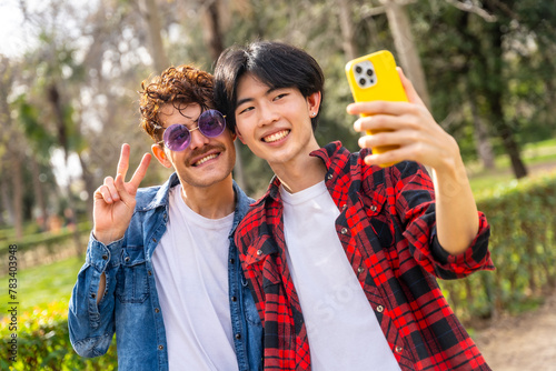 Gay couple gesturing peace and talking selfie in a park