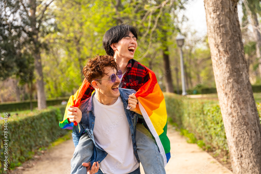 Fototapeta premium Happy gay couple piggybacking and laughing in a park