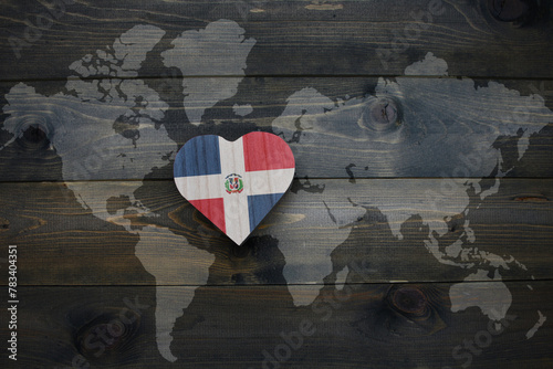 wooden heart with national flag of dominican republic near world map on the wooden background.
