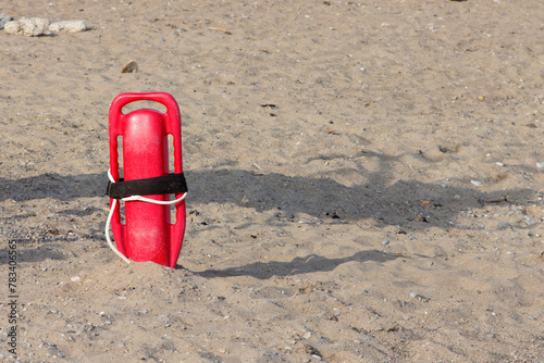 Fotografie A red lifeguard's rescue float stuck in the sand on a beach