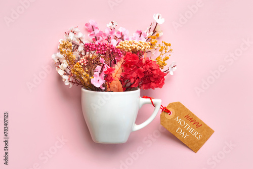 Happy Mother's Day. White cup of coffee with various flowers and brown sale tag with the text Happy Mothers day