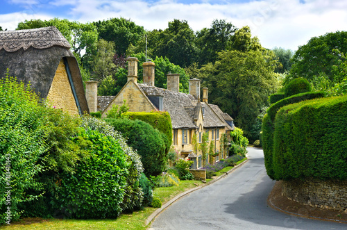 Beautiful street in a Cotswolds village with thatched roof house, Gloucestershire, England photo