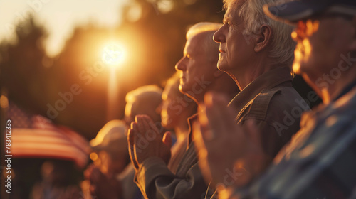 A poignant scene of veterans placing their hands over their hearts as the national anthem plays, gathered around a flagpole. The setting sun casts a soft glow, enhancing the emotio photo