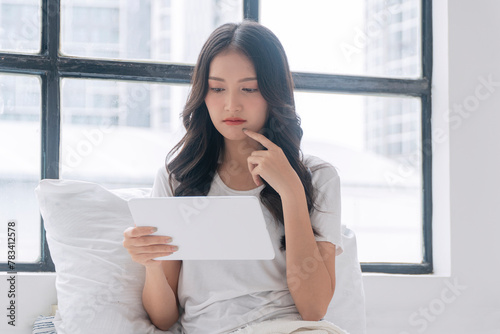 Thoughtful asian woman looking problem investment in tablet sitting on bed white pillow at apartment. Freelance young girl looking screen tablet information finance upset worried thinking. Technology. Free Download Thoughtful asian woman looking problem investment in tablet sitting on bed white pillow at apartment. Freelance young girl looking screen tablet information finance upset worried thinking. Technology. - GFXLoad