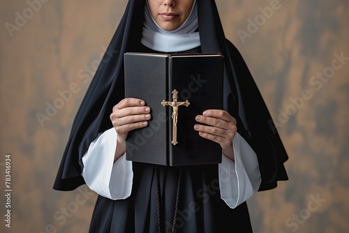 A nun holding a book with a cross prominently displayed on the cover. photo