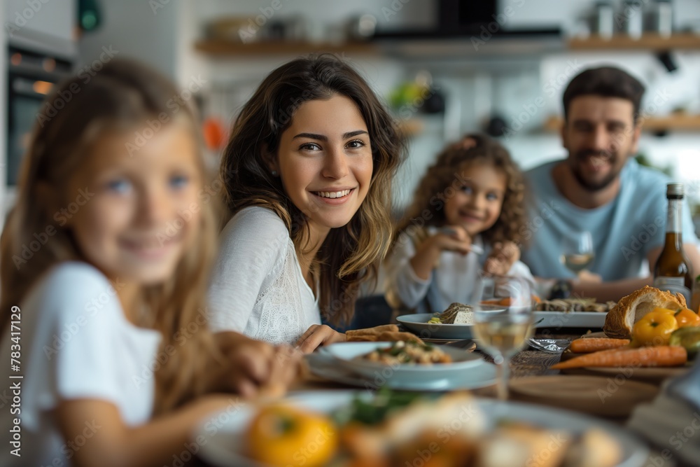 A group of people, likely a happy family, gathered around a table in a kitchen, enjoying a meal together.