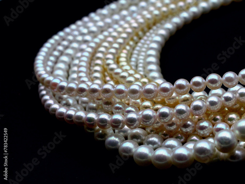 Expensive and luxurious Japanese saltwater Akoya pearls on strands of white, pink and golden organic gems ready to be made into necklaces and sold in jewelry store. photo