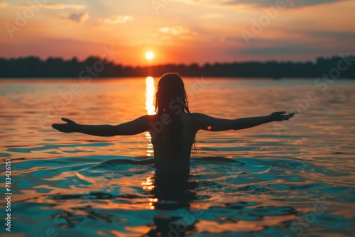 Woman silhouette is in the water, with her arms outstretched. Summer vacation concept, background © top images