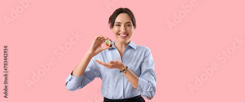 Happy young woman with tasty maki roll on pink background