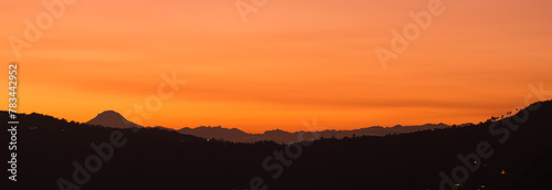 Mountain range silhouette in landscape of yellow sunset 