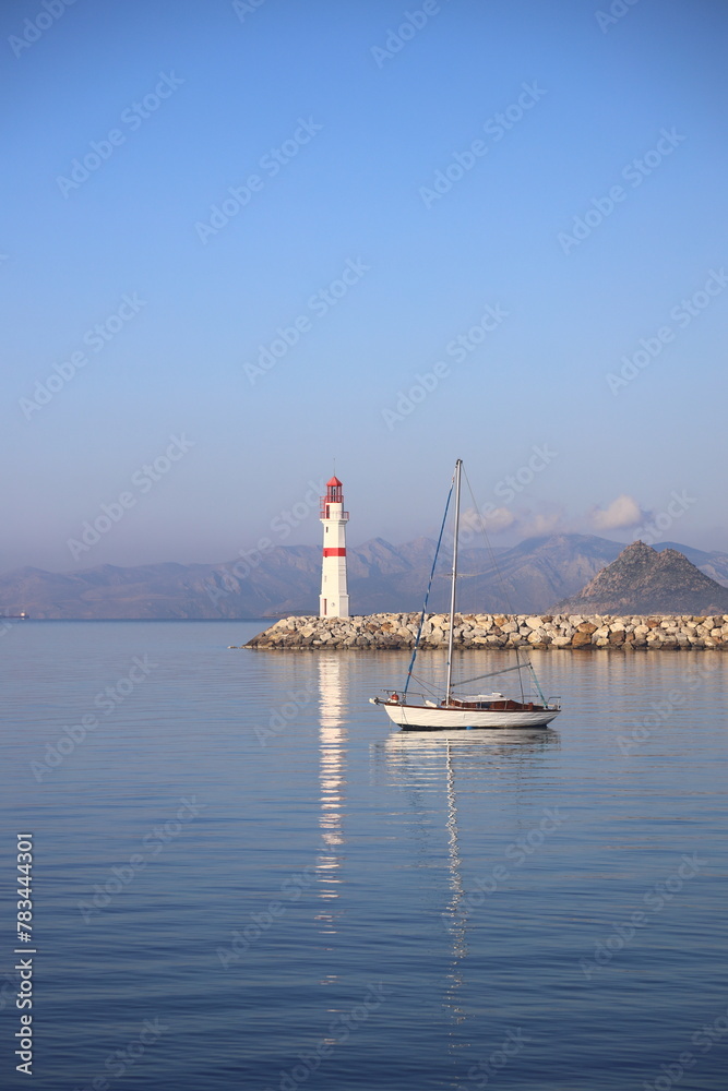 Seascape at sunshine. Lighthouse and sailings on the coast. Seaside town of Turgutreis and spectacular sunshine Seascape at sunshine. Lighthouse and sailings on the coast. Seaside town of Turgutreis and spectacular sunshine