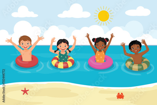 Cute little multi-ethnic kids with inflatable rings having fun in the sea at the beach