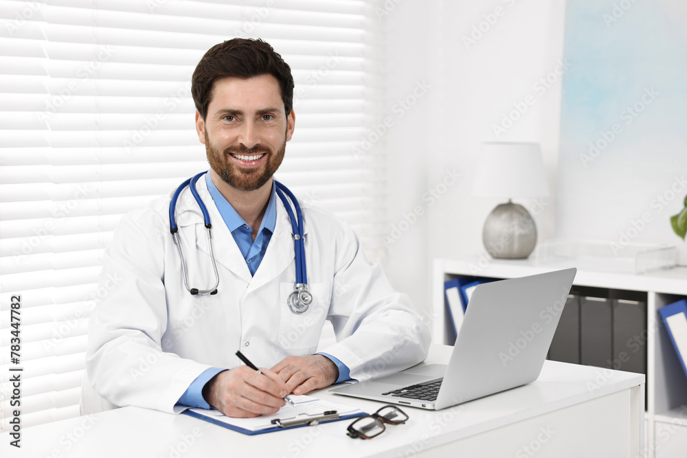 Medical consultant with stethoscope at table in clinic