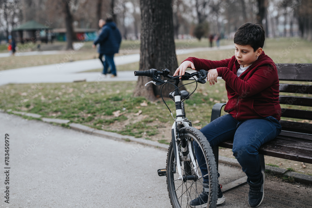 A joyful young kid rests on a bench with his bike in the park, reflecting an active lifestyle outdoors.