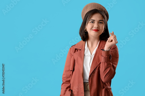 Portrait of fashionable young woman in beret on blue background