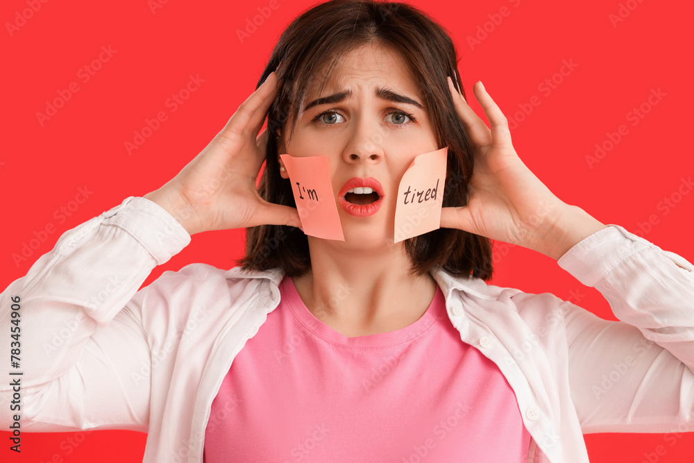 Beautiful young stressed woman and sticky notes with text I'M TIRED on red background. Stress Awareness Month - obrazy, fototapety, plakaty 