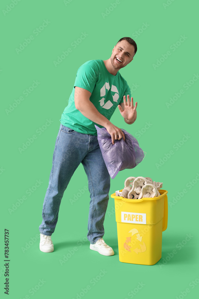 Male volunteer with garbage bag and recycle bin for paper on green background Male volunteer with garbage bag and recycle bin for paper on green background