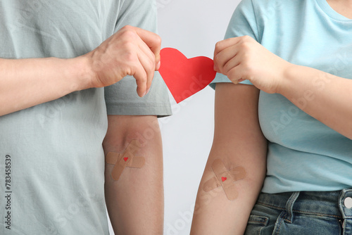 Blood donors with applied medical patches and paper heart on grey background, closeup photo