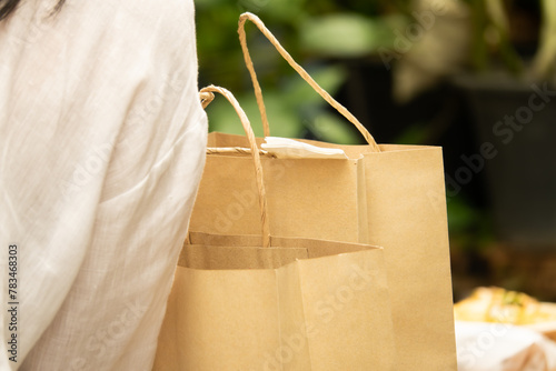 A woman is holding two brown paper bags