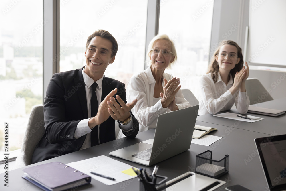 Office employees sit at conference desk in modern board room, listen presentation, clapping at group meeting, making successful deal, greeting business coach start or finish seminar express respect Office employees sit at conference desk in modern board room, listen presentation, clapping at group meeting, making successful deal, greeting business coach start or finish seminar express respect