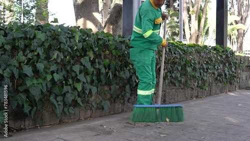 a cleaning worker who is sweeping the street in a park with a broom