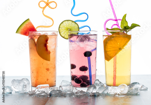 Three fresh fruit spritzers surrounded by ice and garnished with funky straws. photo