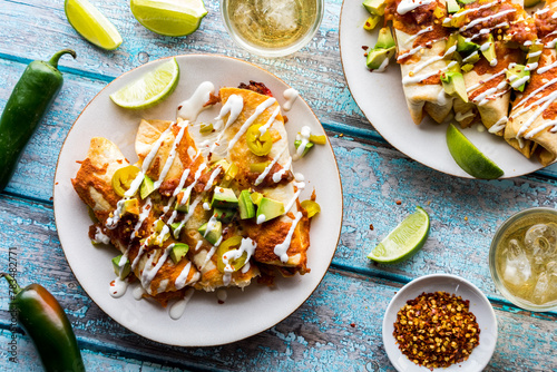 Plates of taquitos topped with salsa, avocado and sour cream drizzle. photo