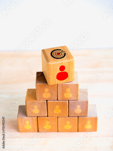 Leadership, leader, manager, followers, business team concepts. Target goal symbol and red person icon on top of many people icon on wood blocks stacked pyramid shape on white vertical background.