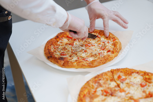 close-up. man cutting large margherita pizza on the table with appetizers 