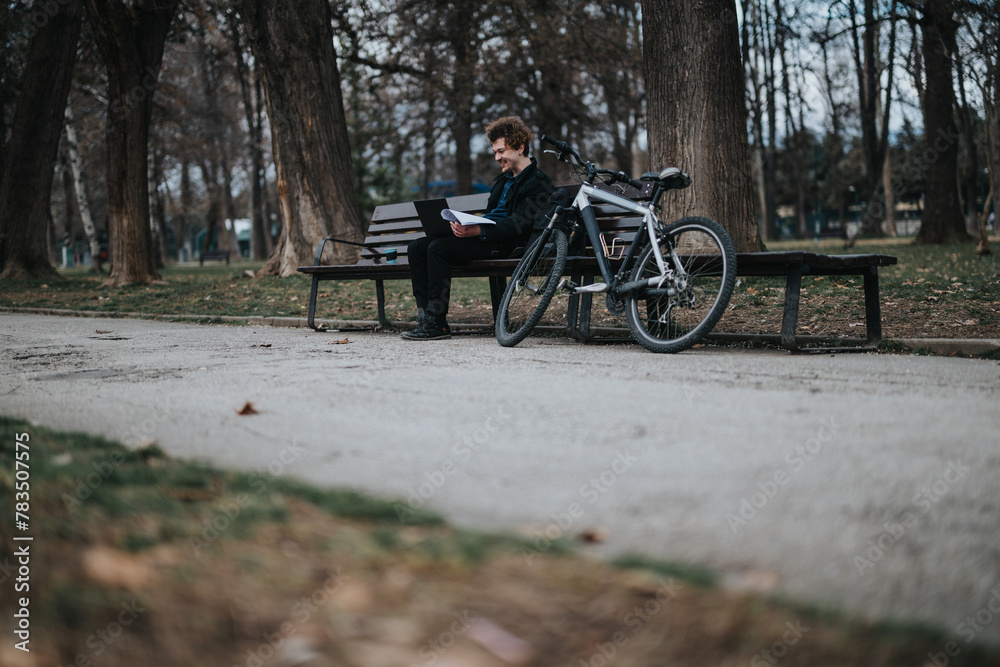 An entrepreneurial man sits on a park bench next to his bicycle, reviewing documents with focus and serenity.