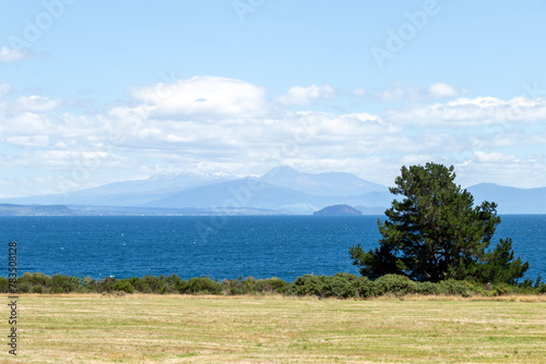 View from Lake Taupo lookout: turquoise waters of the crater lake against the stunning backdrop of the Taranaki Mountains, North Island, New Zealand