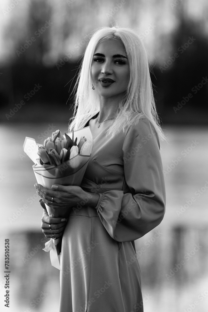 Fototapeta premium Portrait of a young beautiful blonde girl outdoors. Black and white photo.