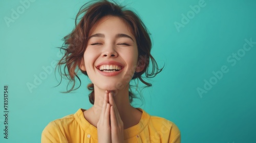 A woman smiling and praying with her hands on her chest.