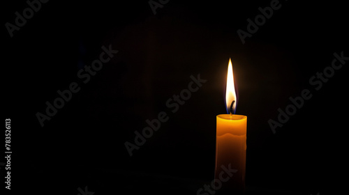 One thin isolated lit up orange candle on black background