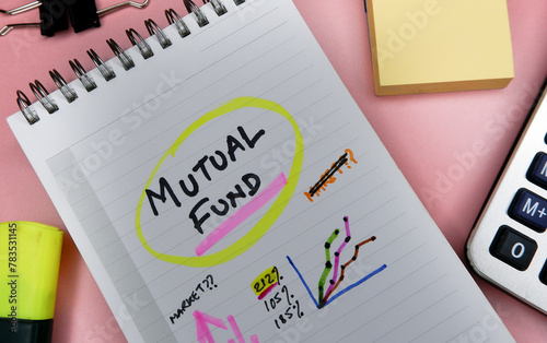 Concept of mutual fund written on note pad while doing planning for investment with graphs.